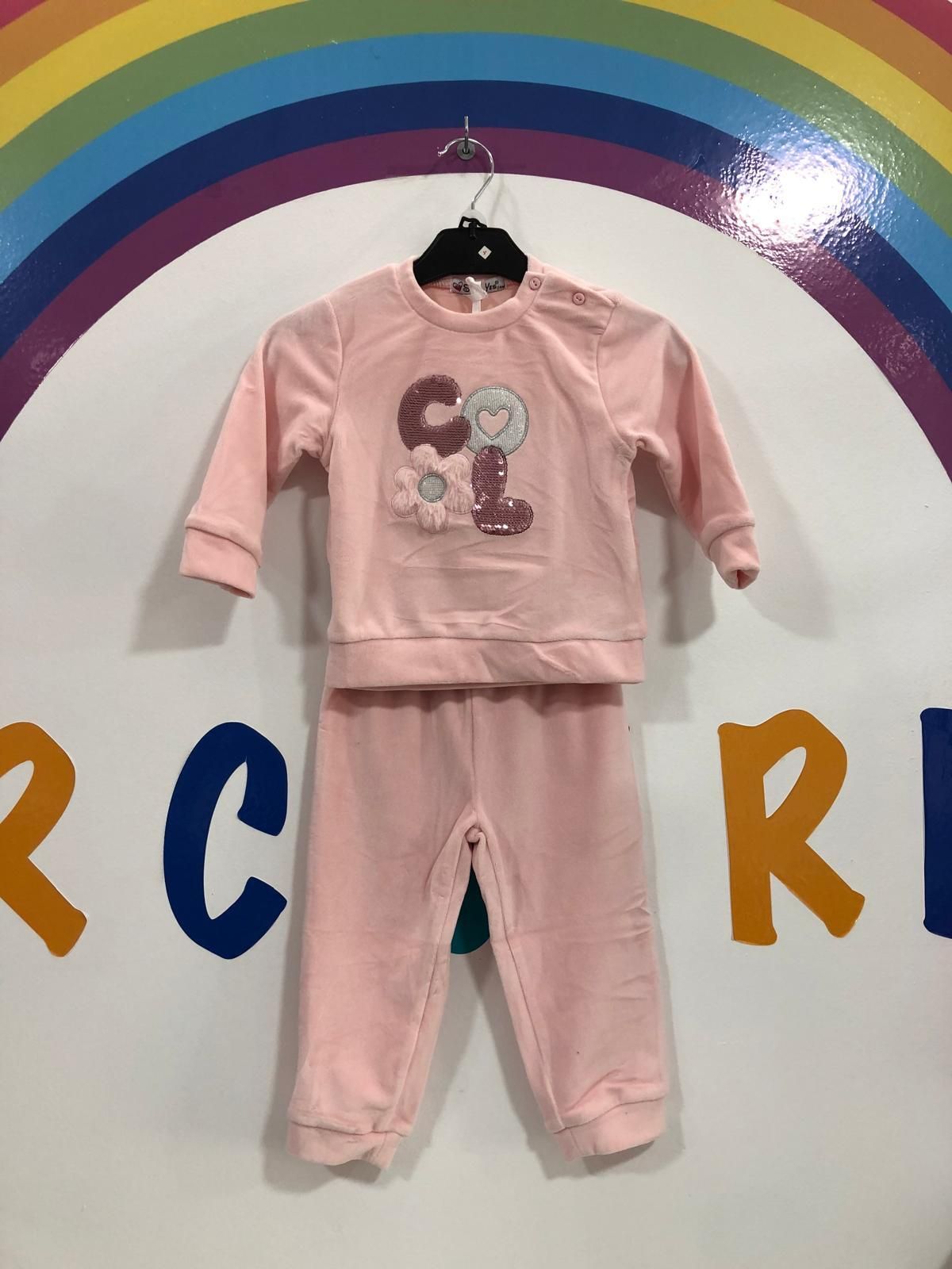 Un traje rosa está colgado en una percha frente a un arcoíris.