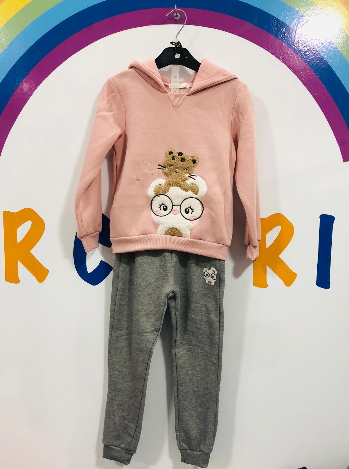 Una sudadera con capucha rosa y unos pantalones grises cuelgan de una percha.