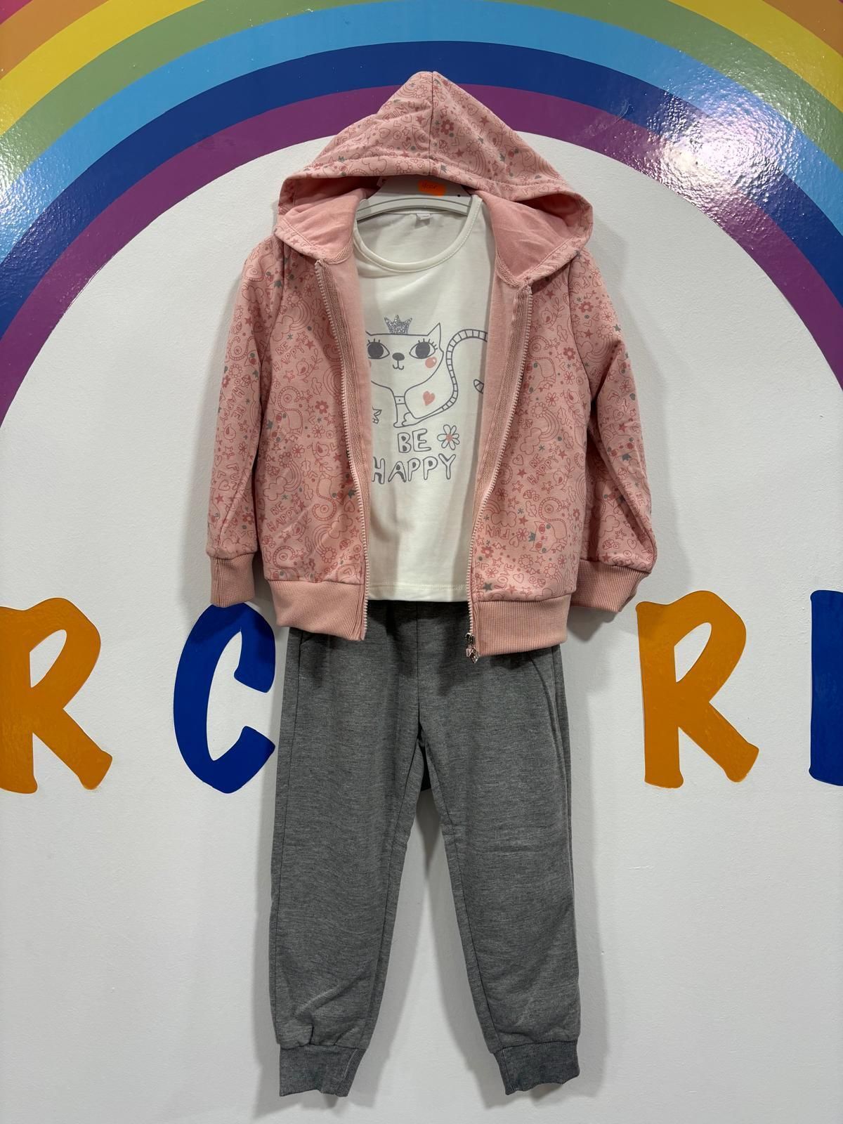 Una chaqueta rosa con un gato está colgada en una percha frente a un arcoíris.