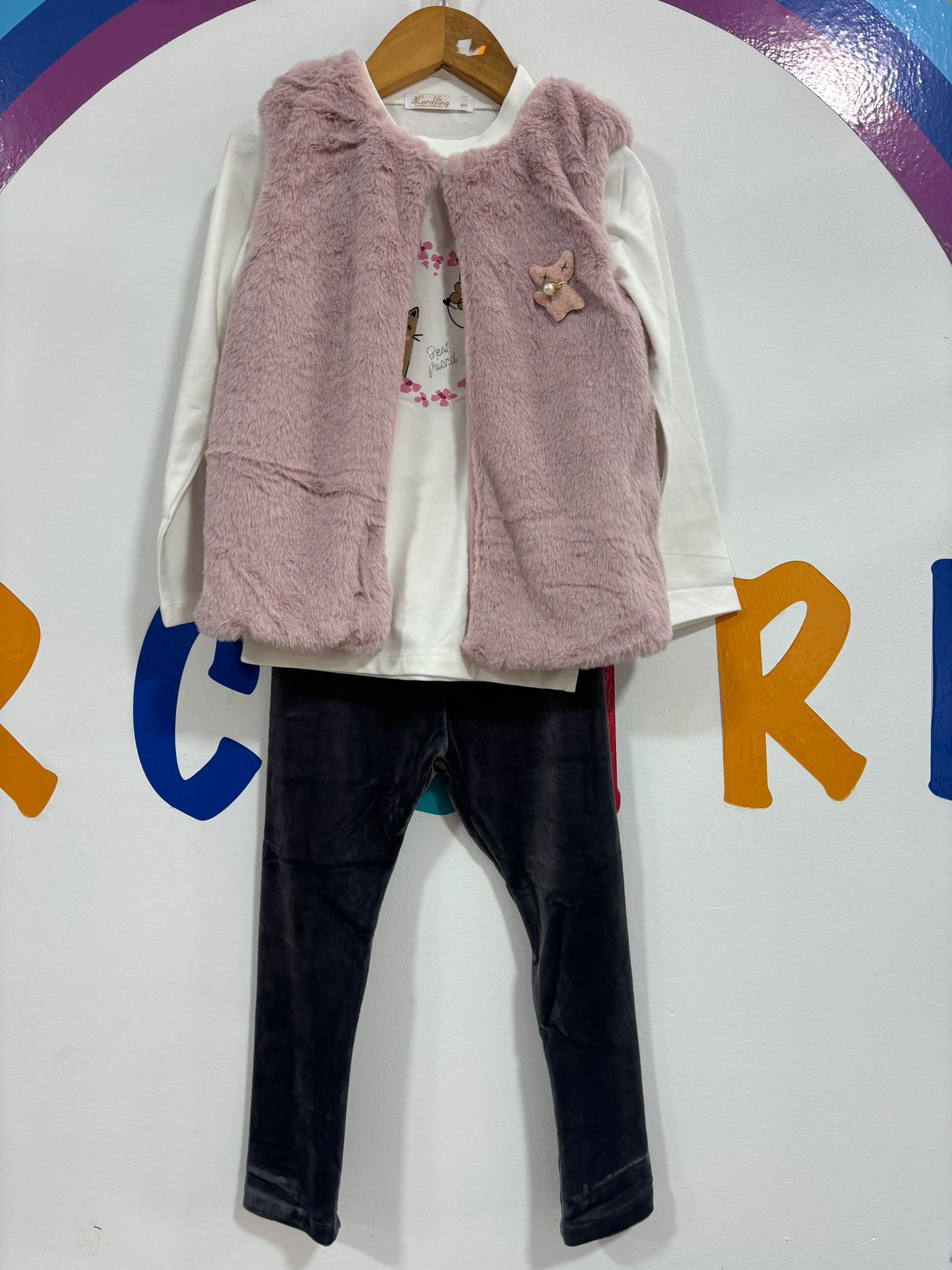 Un niño lleva un chaleco rosa y una camisa blanca.