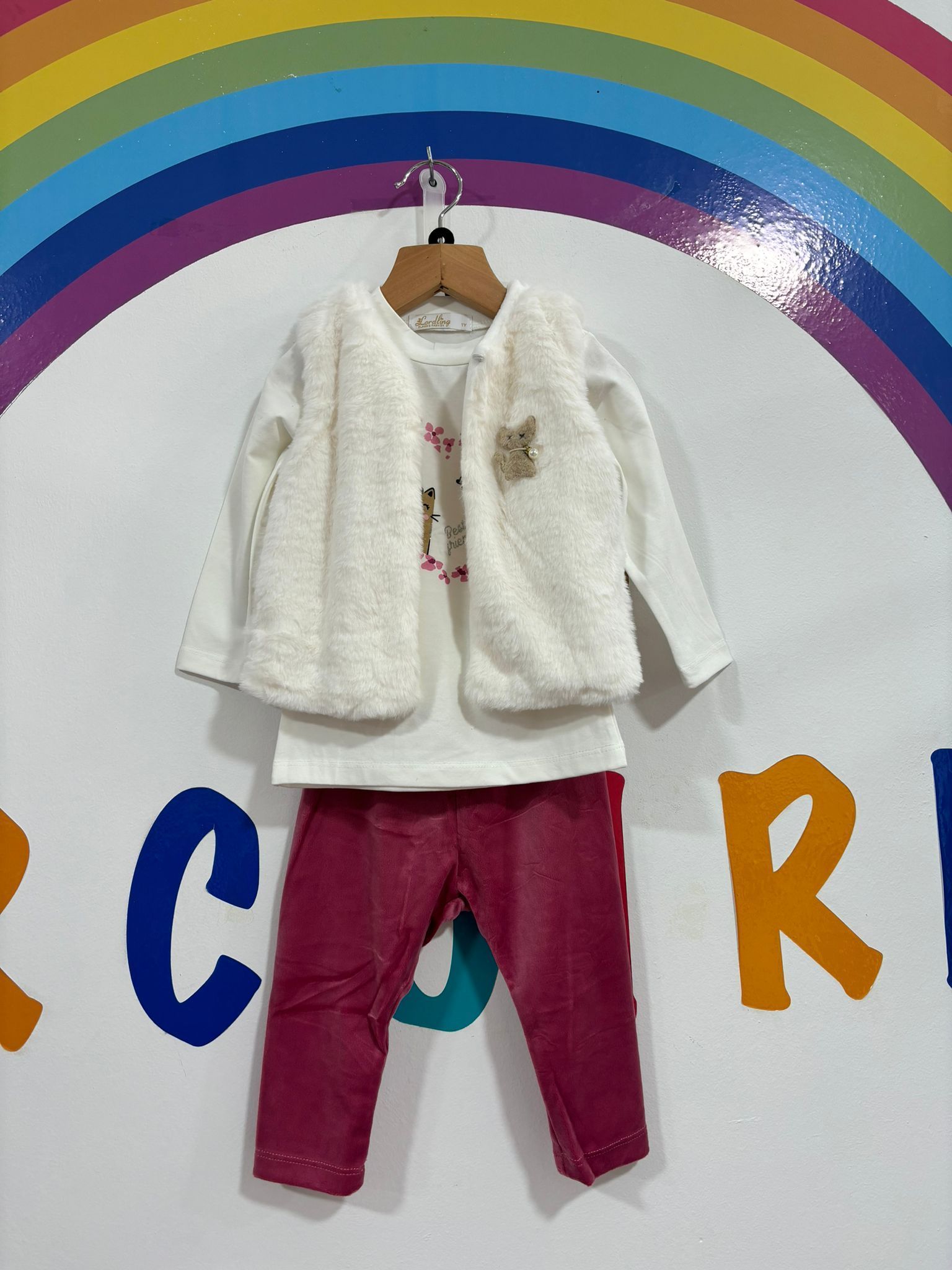 Un bebé que lleva un chaleco blanco y pantalones rosas.