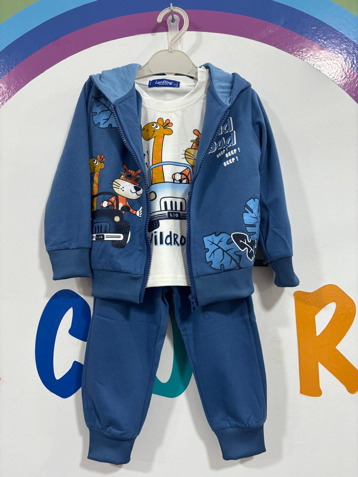 Una chaqueta azul con una jirafa está colgada en una percha.