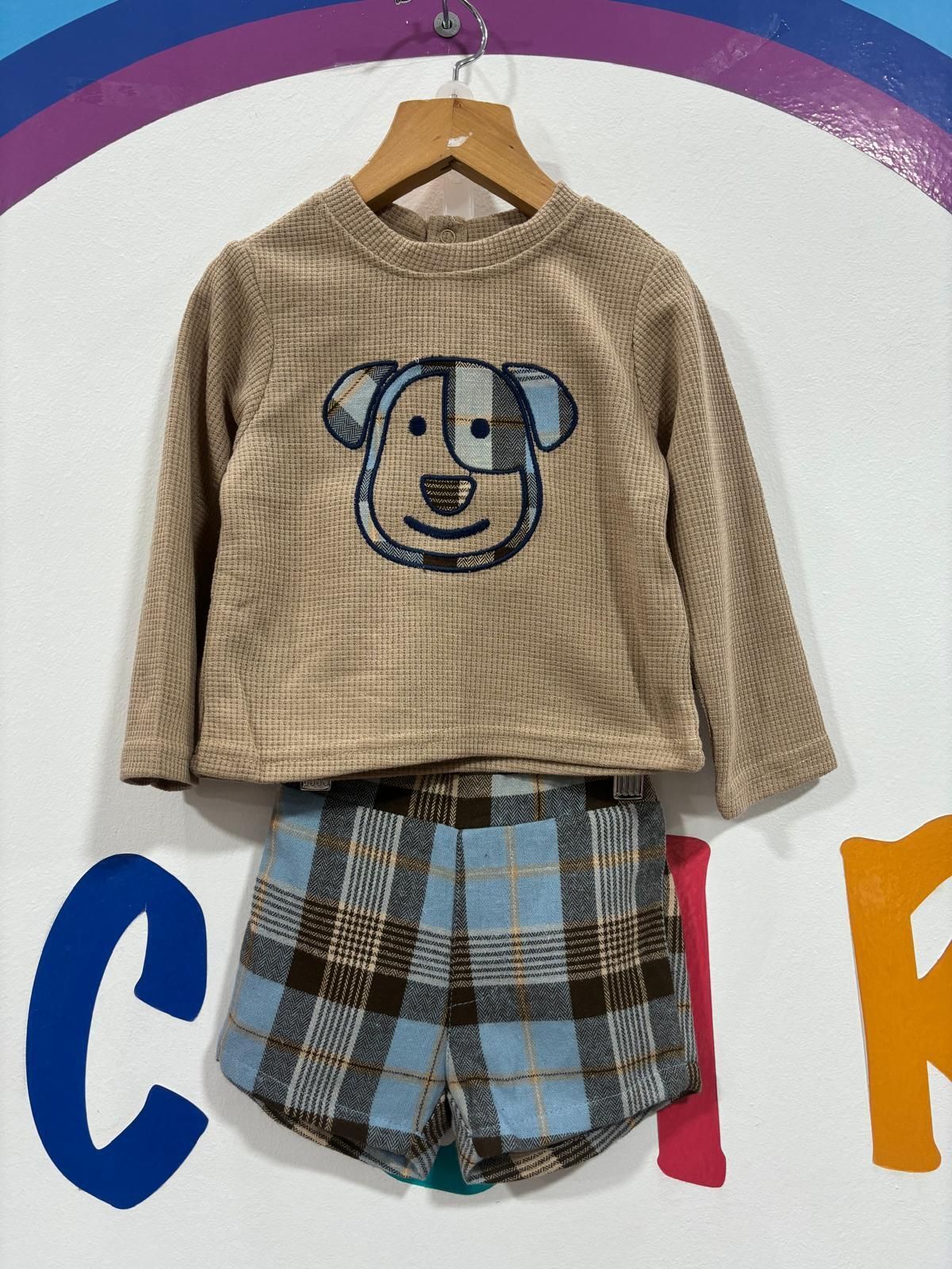 Una camisa con un perro está colgada en una percha.