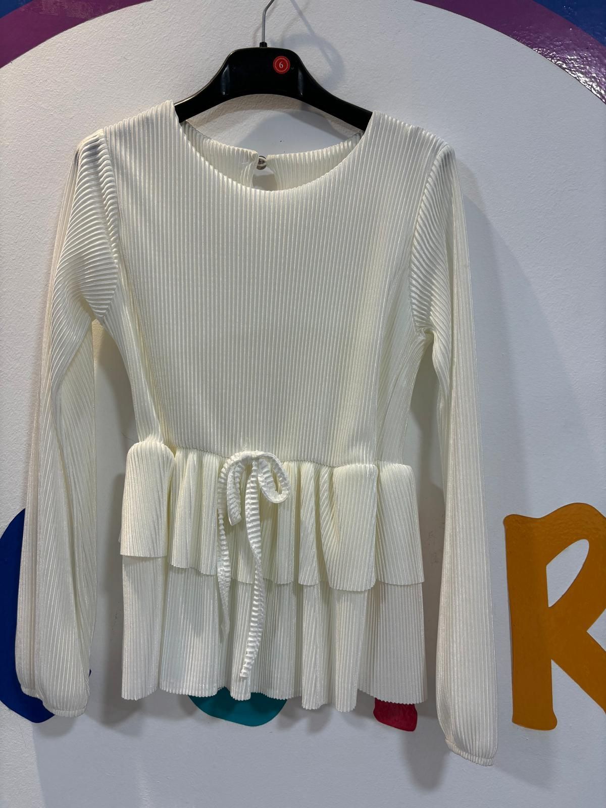 Una camisa blanca con mangas largas está colgada en una percha.