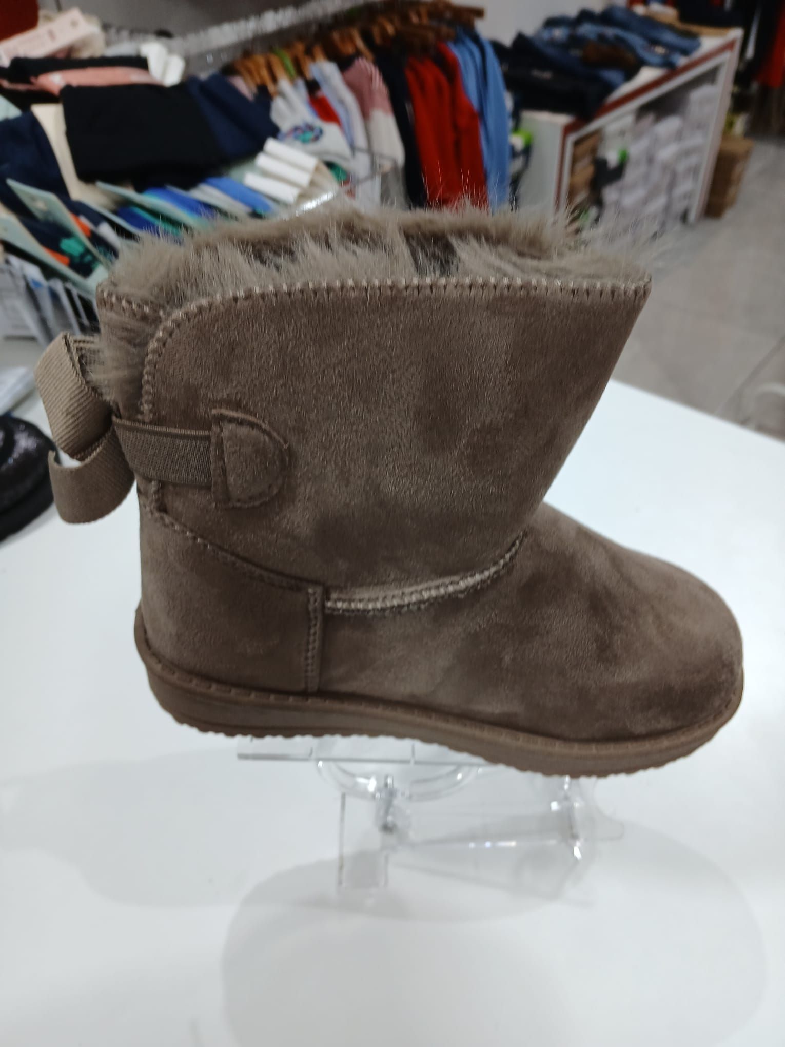 Un par de botas marrones colocadas sobre un expositor transparente.