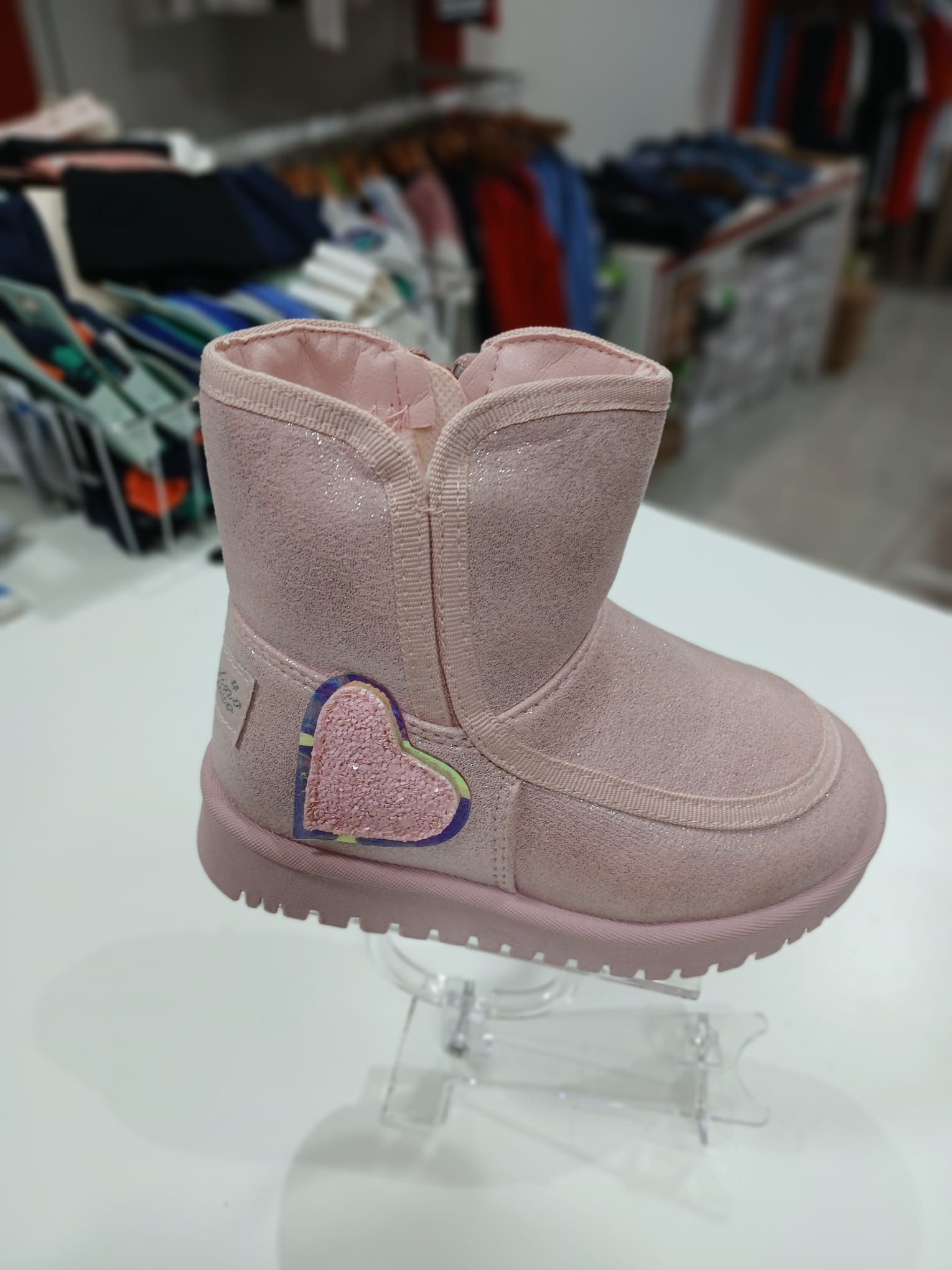 Un par de botas rosas con un corazón en el costado están sobre una mesa.