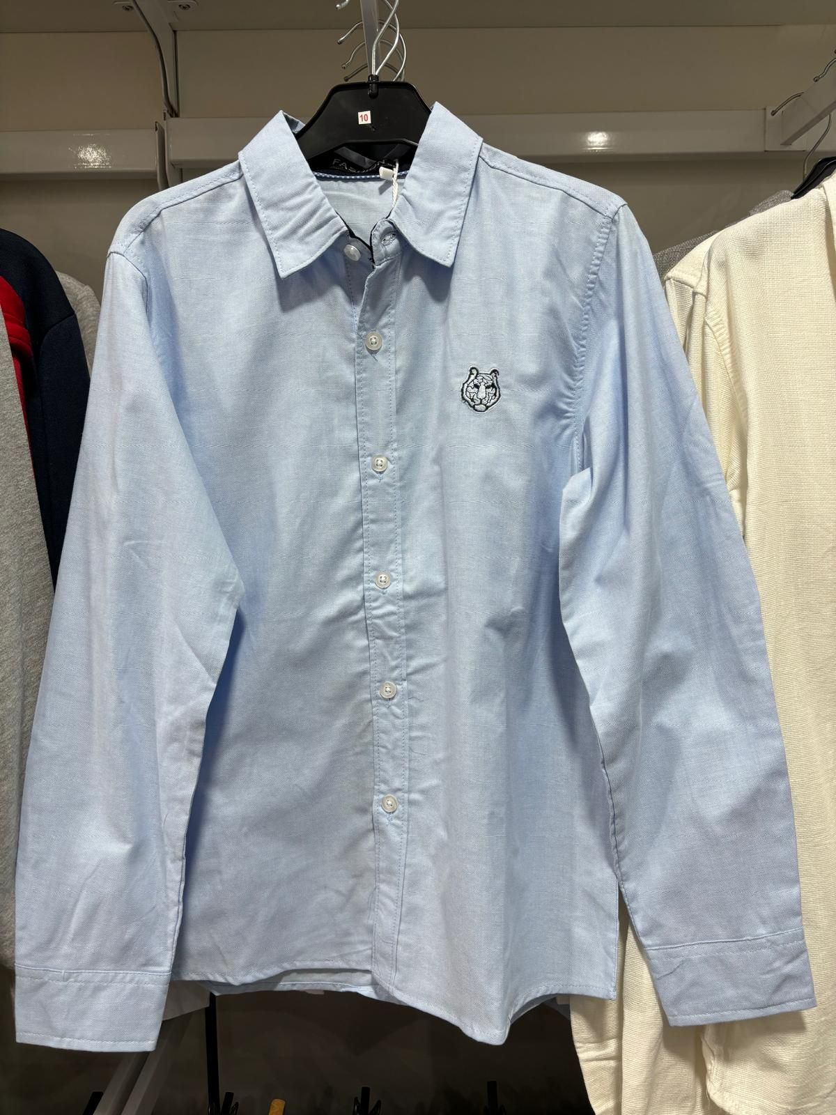 Una camisa azul claro está colgada en una percha en un armario.