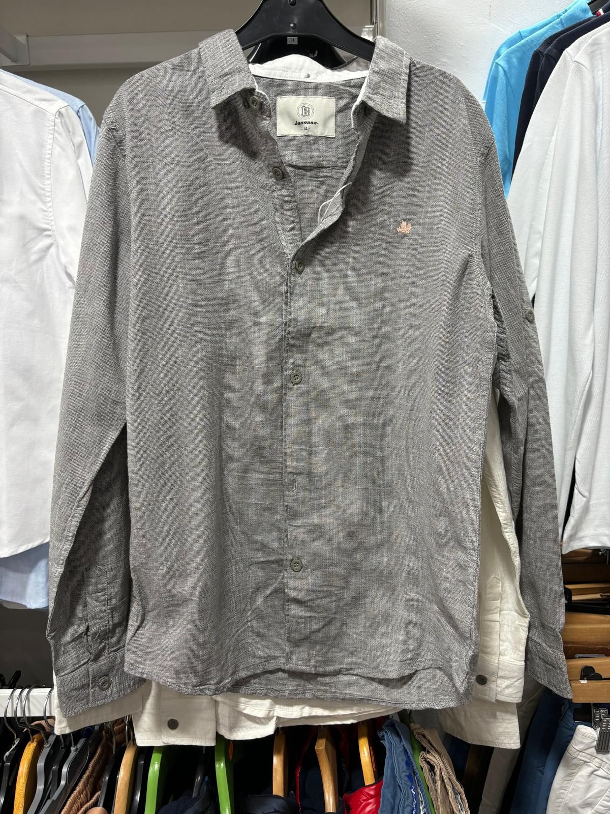 Una camisa gris está colgada en un perchero en un armario.