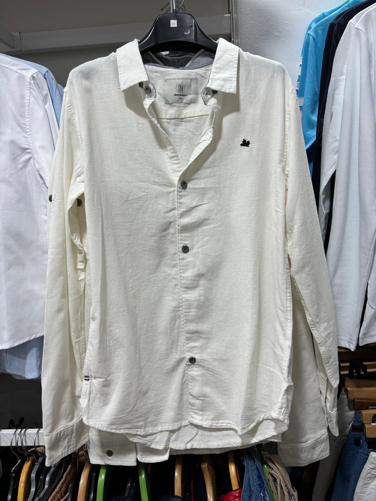 Una camisa blanca está colgada en un perchero en una tienda.