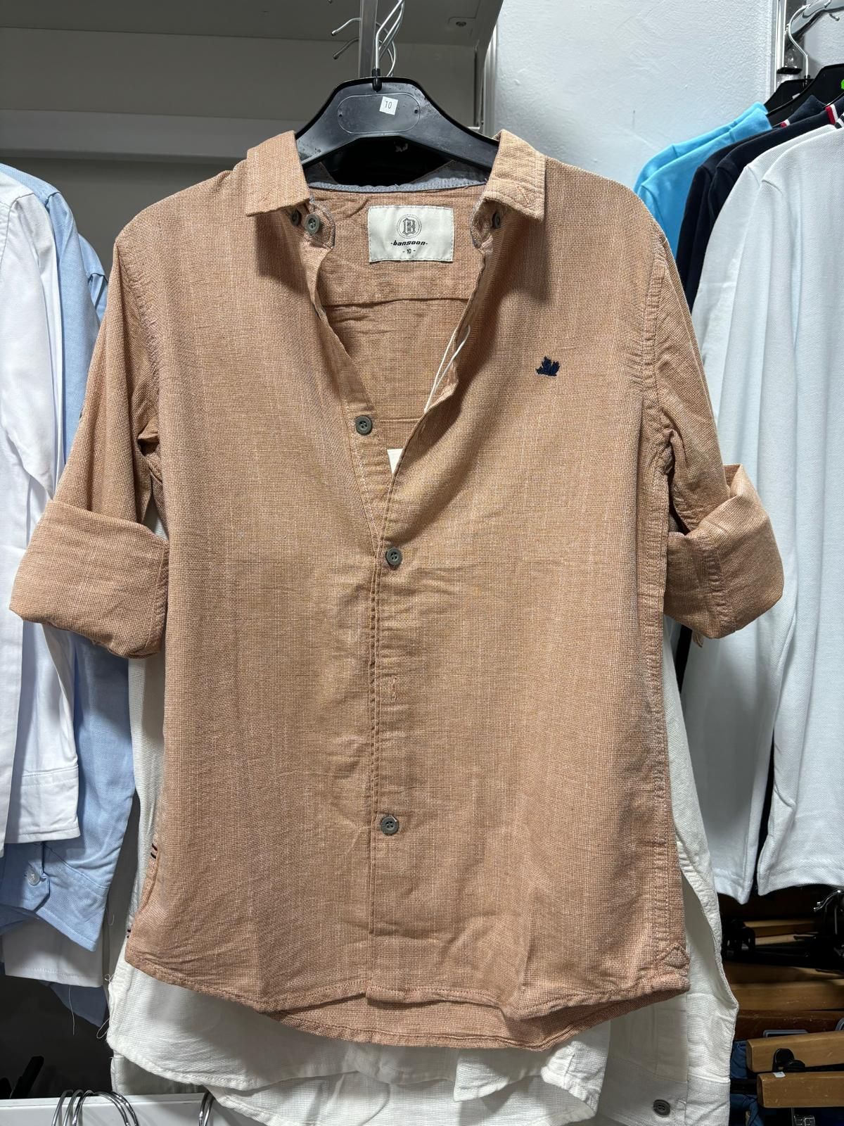 Una camisa marrón está colgada en una percha en una tienda.