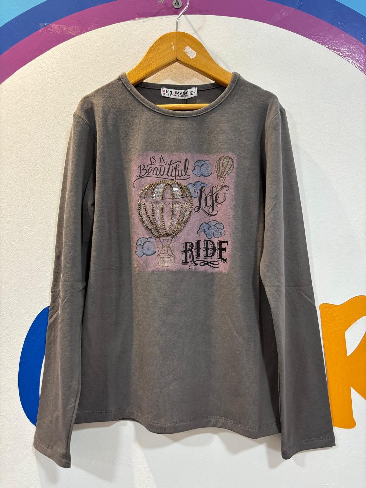 Una camiseta de manga larga con la imagen de un globo aerostático está colgada en una percha.