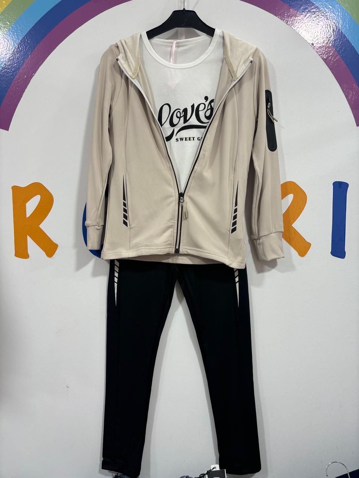 Una sudadera con capucha y unos pantalones están colgados en una percha frente a una pared con la letra r escrita en ella.