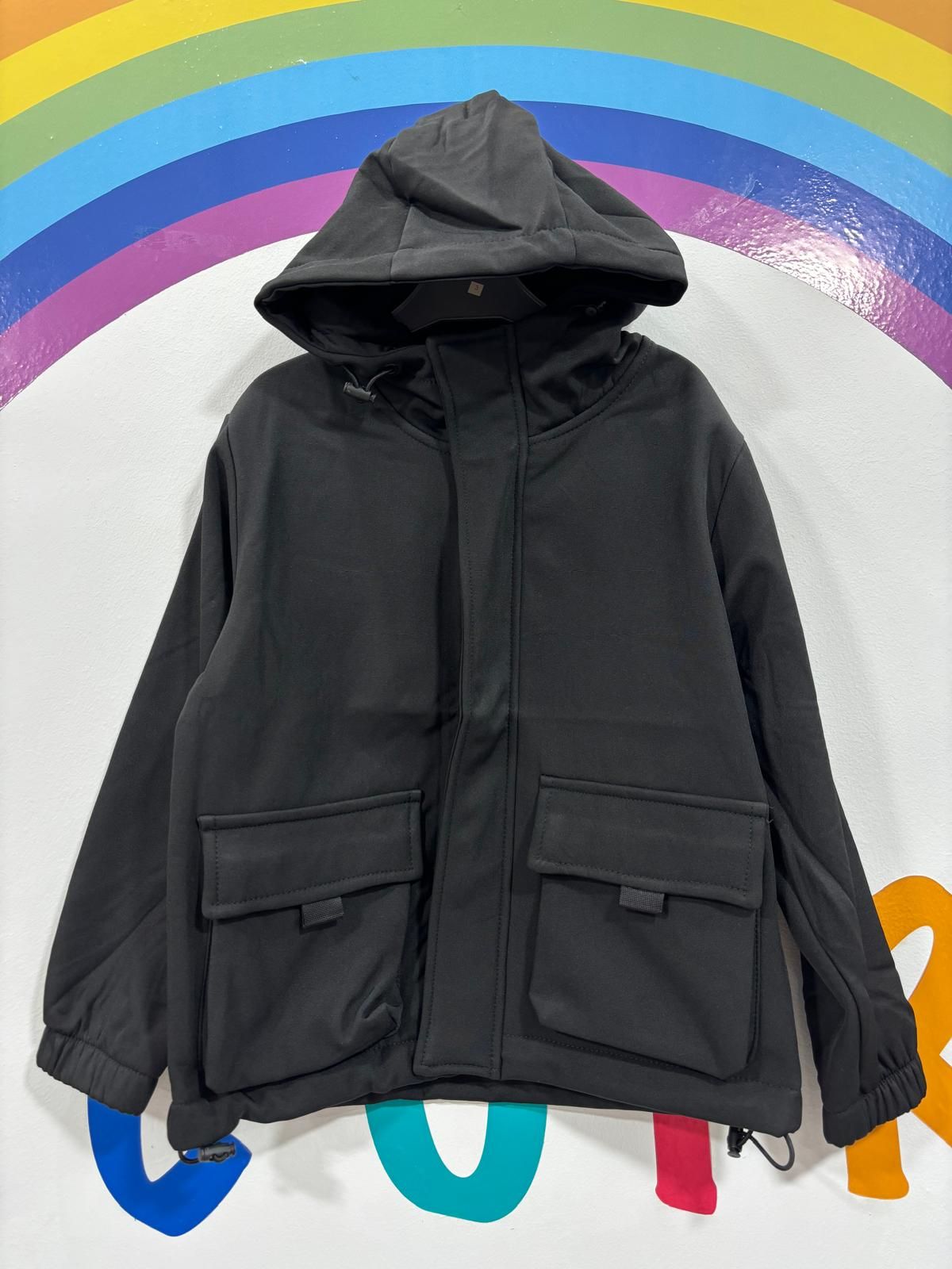 Una chaqueta negra con capucha está sentada frente a un arco iris.