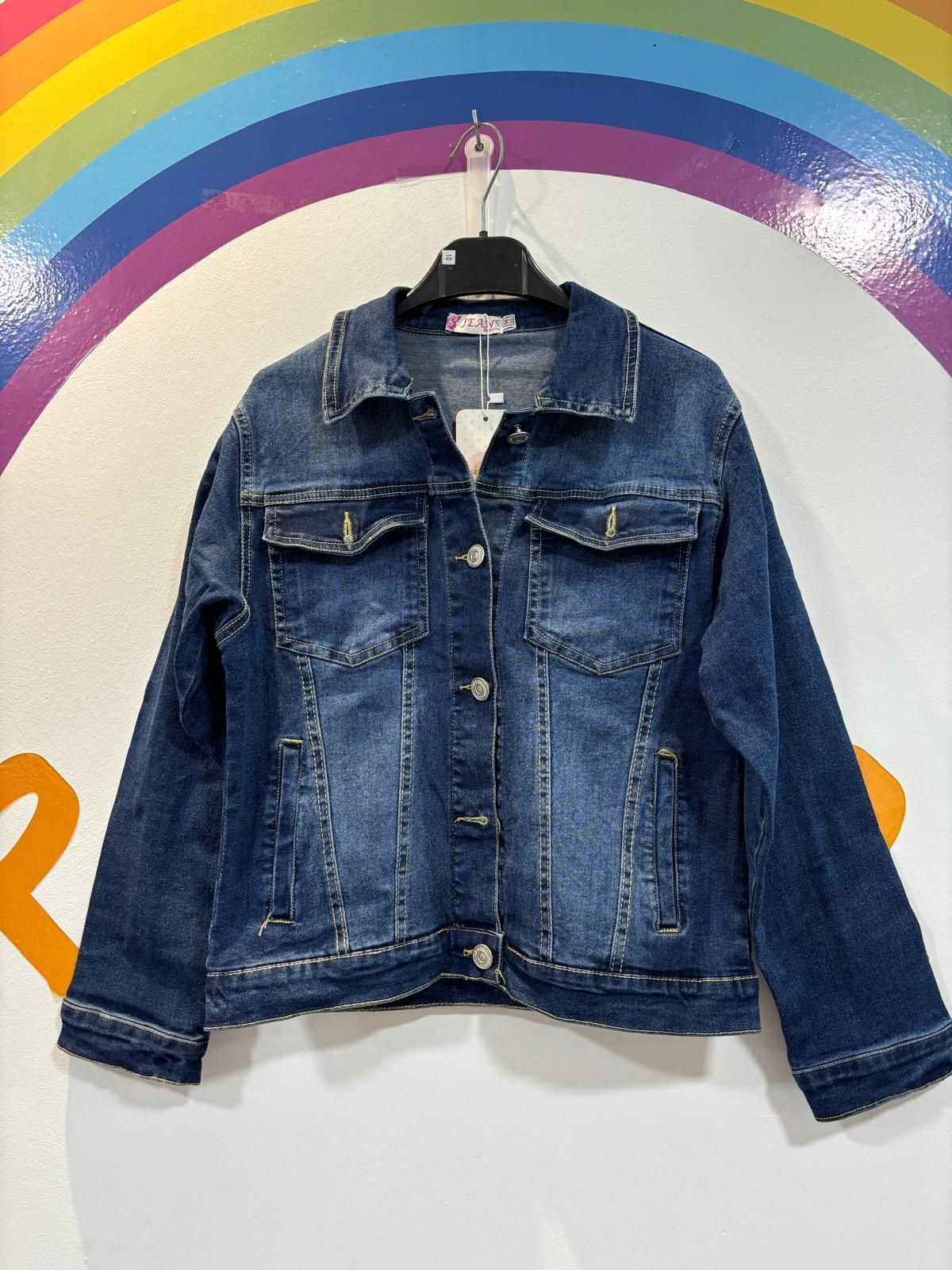 Una chaqueta vaquera cuelga de una percha delante de un arcoíris.