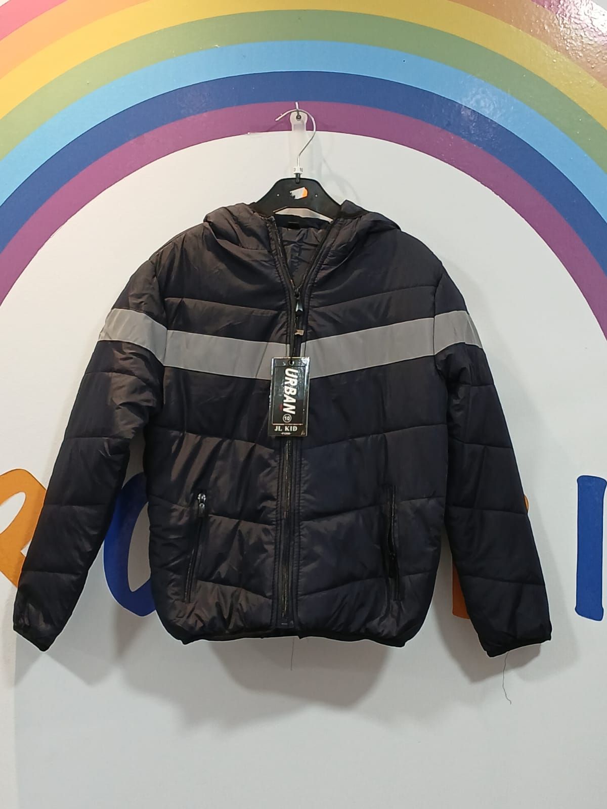 Una chaqueta negra con capucha cuelga de una percha delante de un arco iris.