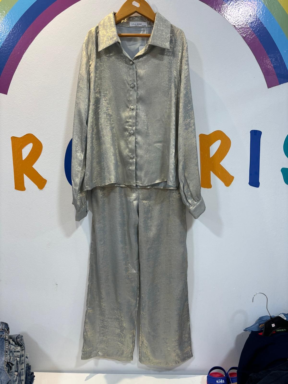 Una camisa y unos pantalones plateados cuelgan de una percha.