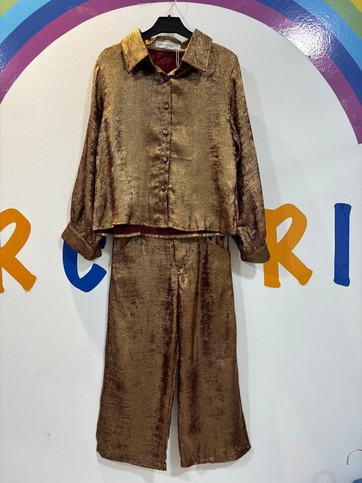 Una camisa y unos pantalones dorados están colgados en una percha.