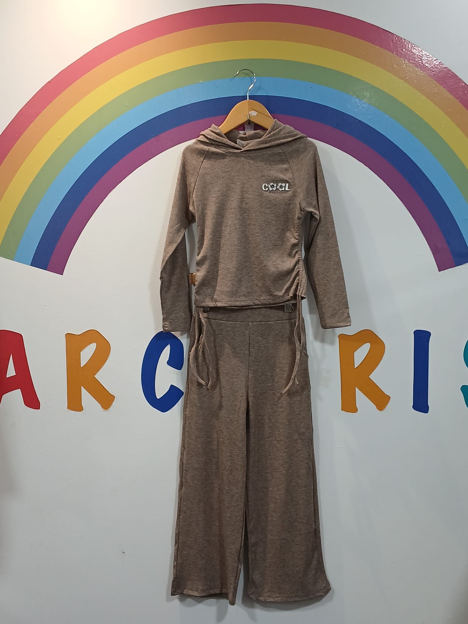 Una sudadera con capucha y unos pantalones cuelgan de una percha delante de un arcoíris.