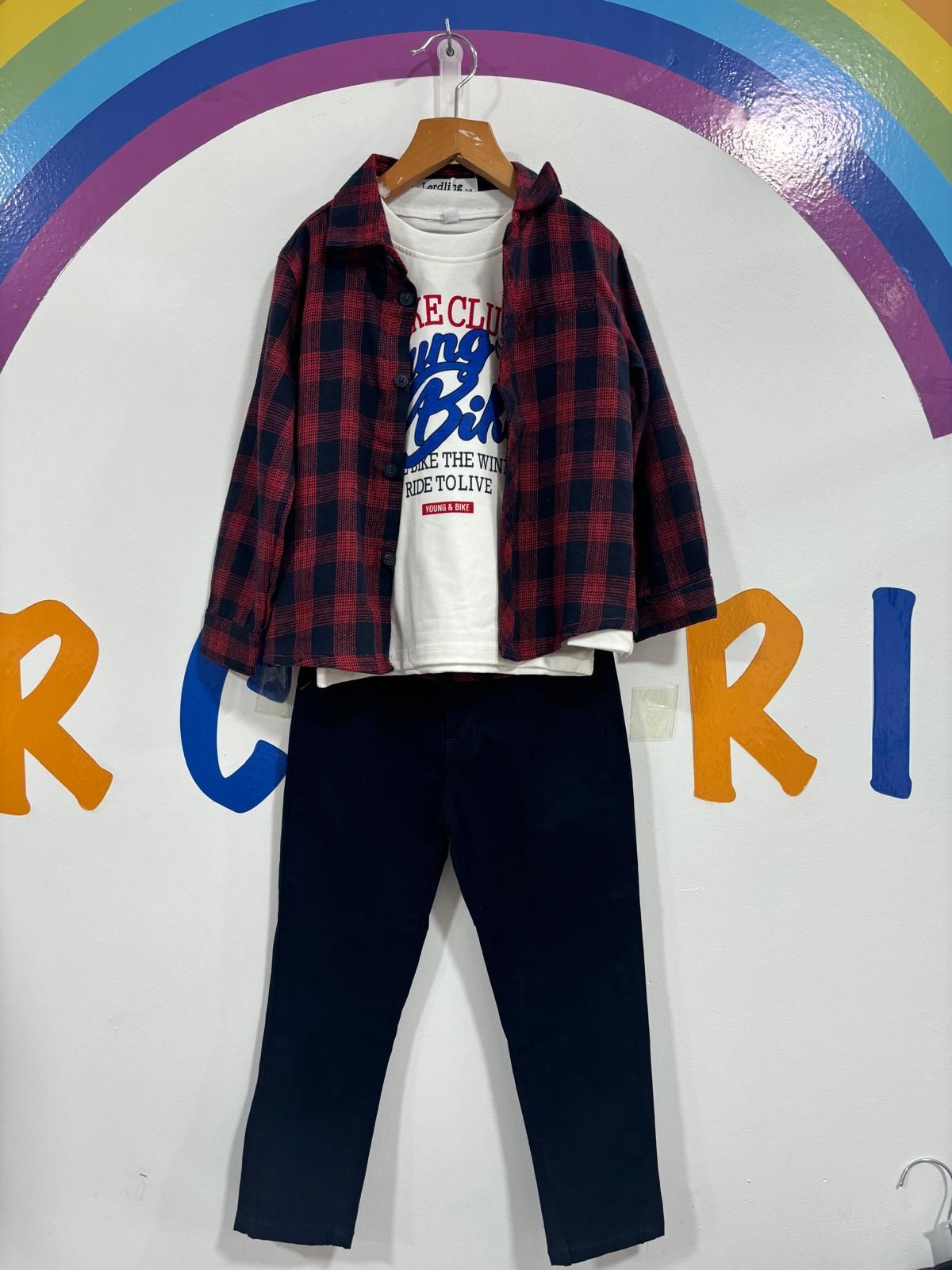 El atuendo de un niño está colgado en una percha frente a un arcoíris.