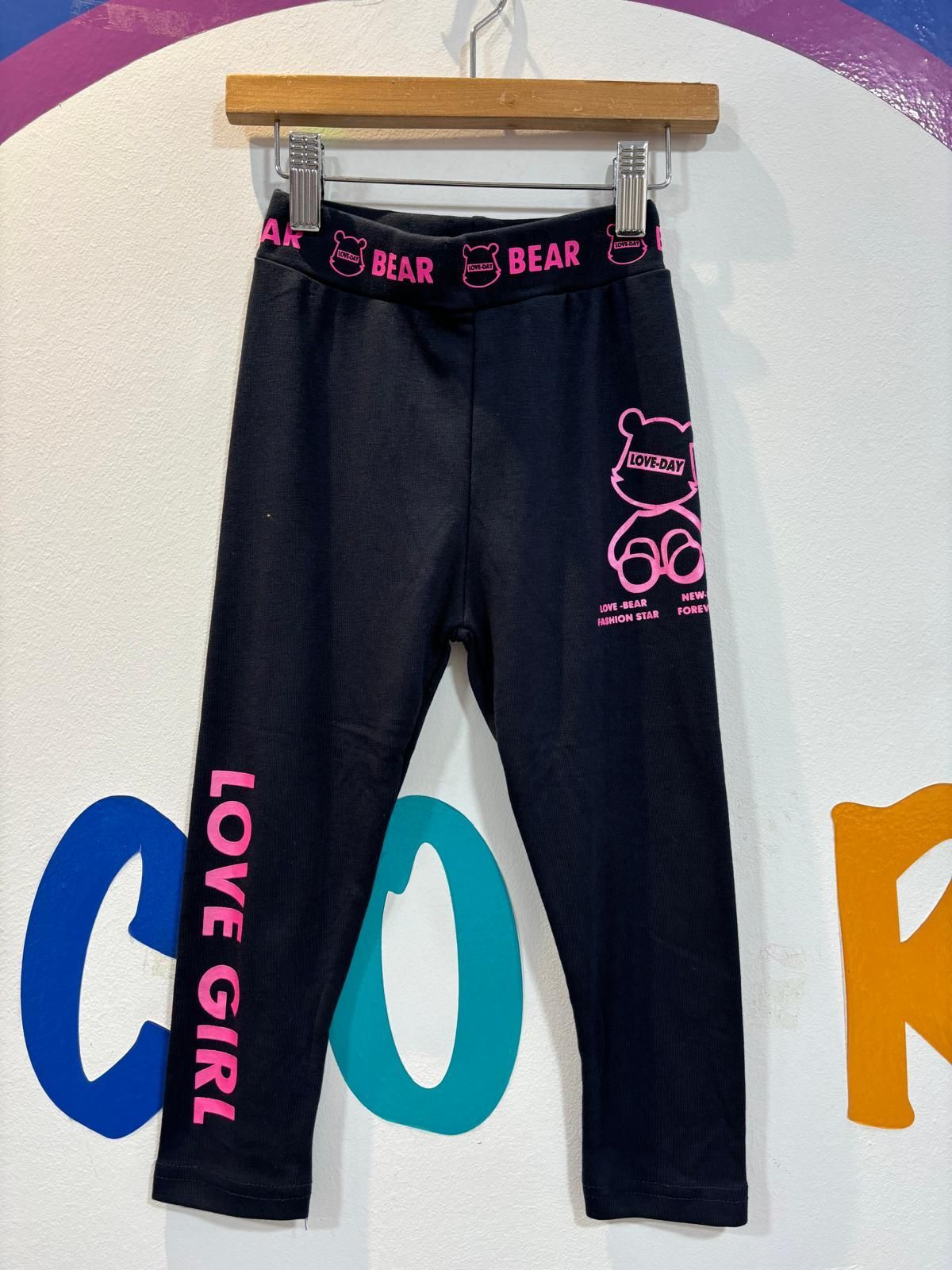 Un par de leggings negros de Love Girl colgados en una percha.