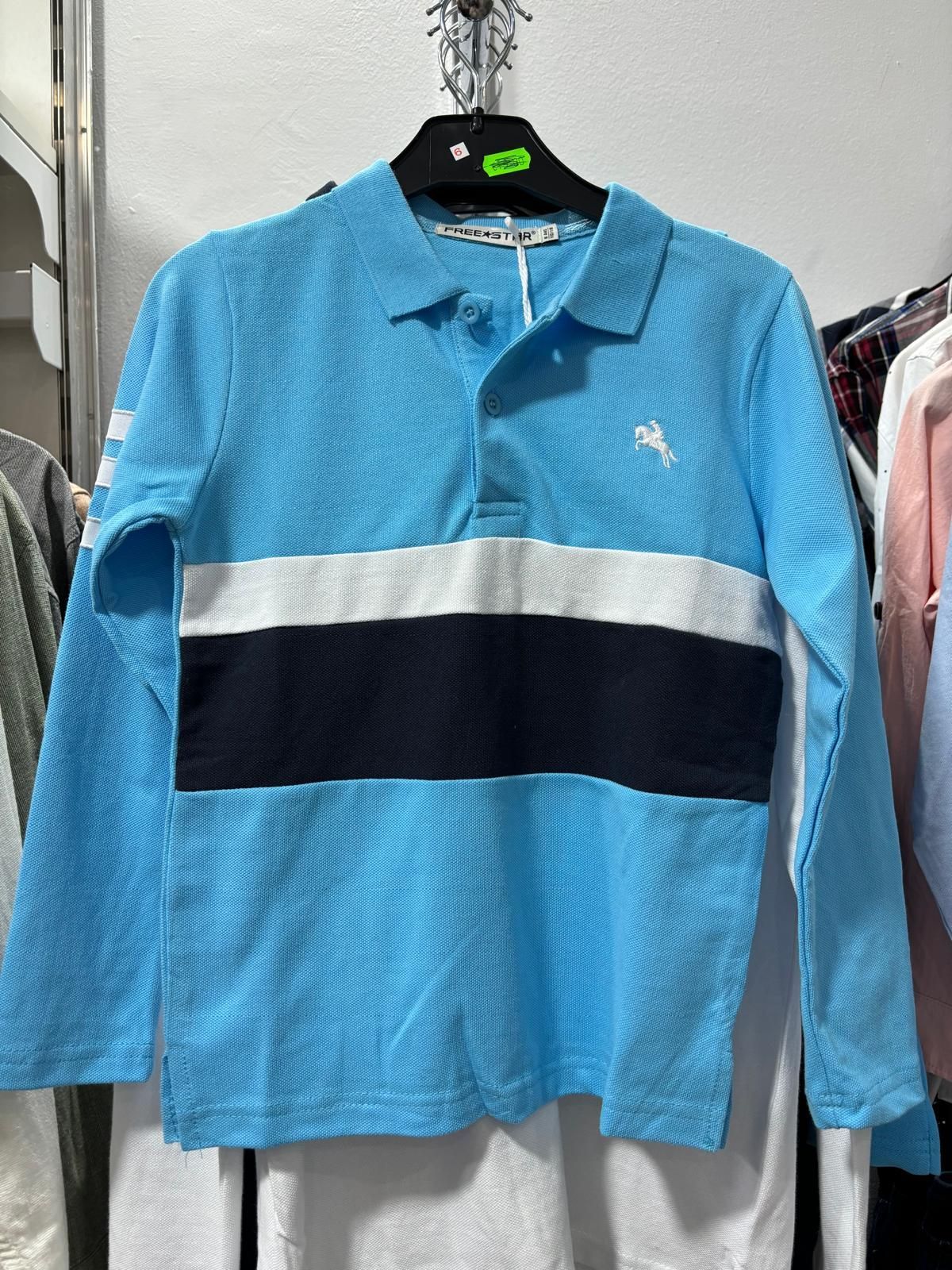 Una camisa polo azul y negra está colgada en una percha.