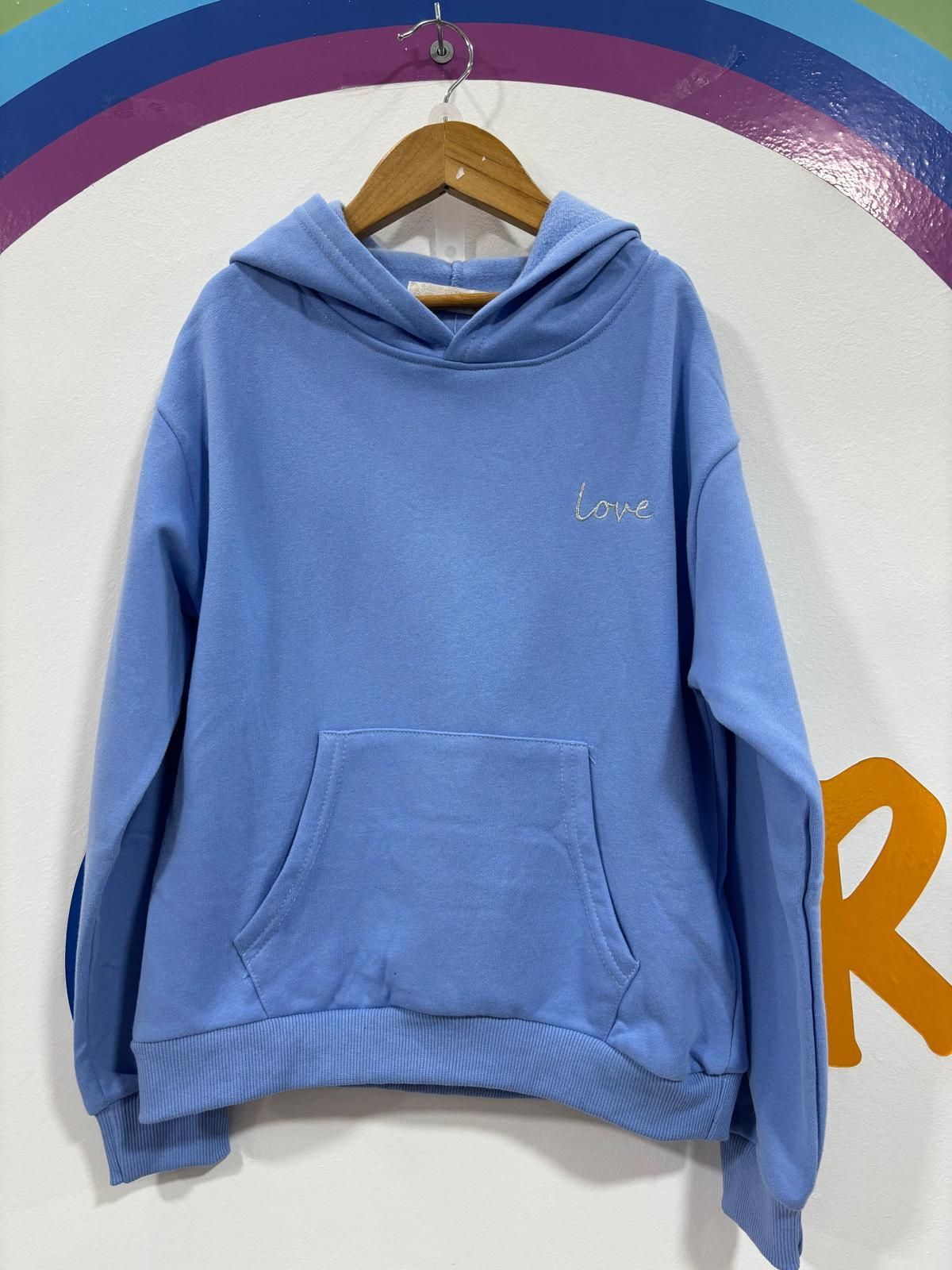 Una sudadera con capucha azul claro está colgada en una percha.