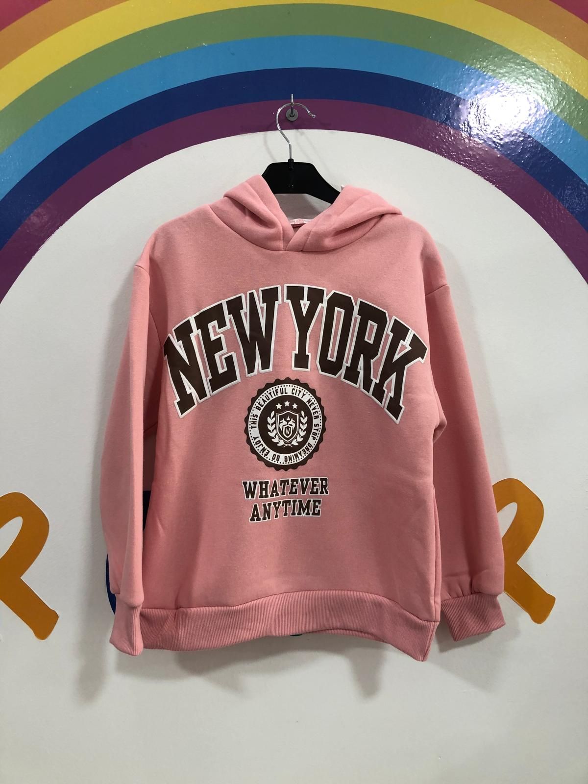 Una sudadera con capucha rosa de Nueva York está colgada en una percha.