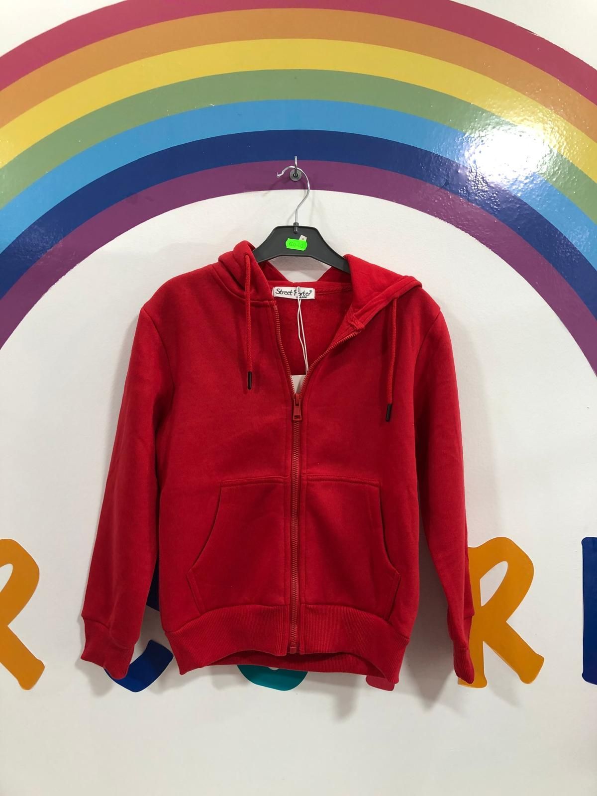 Una sudadera con capucha roja está colgada en una percha frente a un arcoíris.