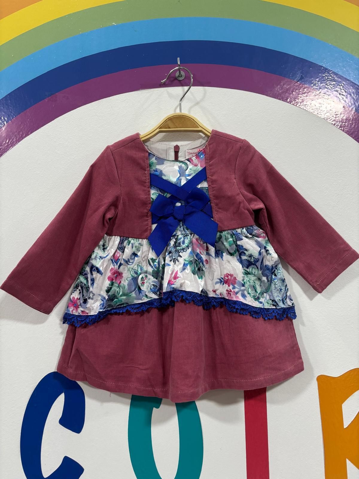 El vestido de una niña está colgado en una percha delante de un arco iris.