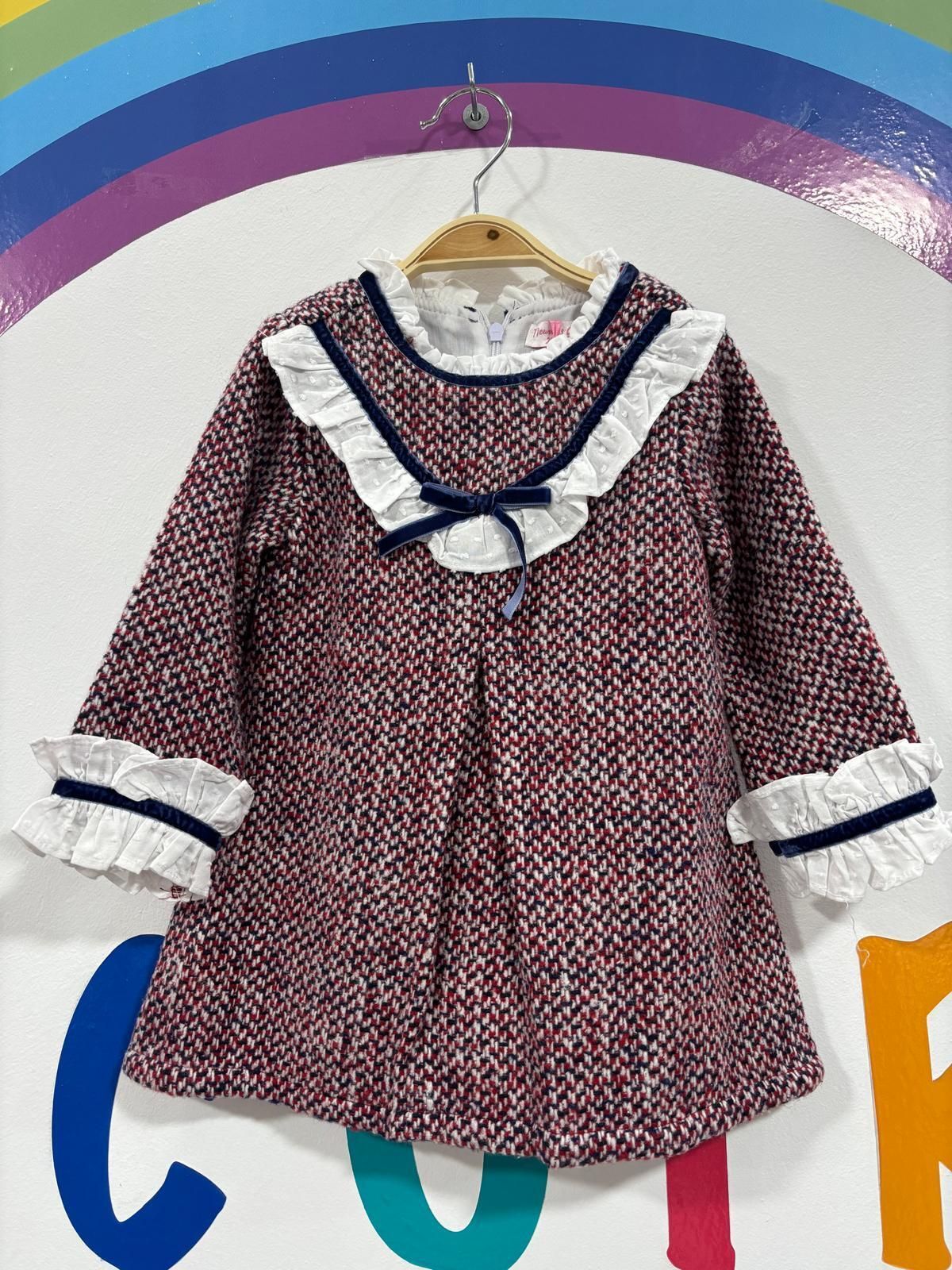 El vestido de una niña está colgado en una percha frente a un arcoíris.