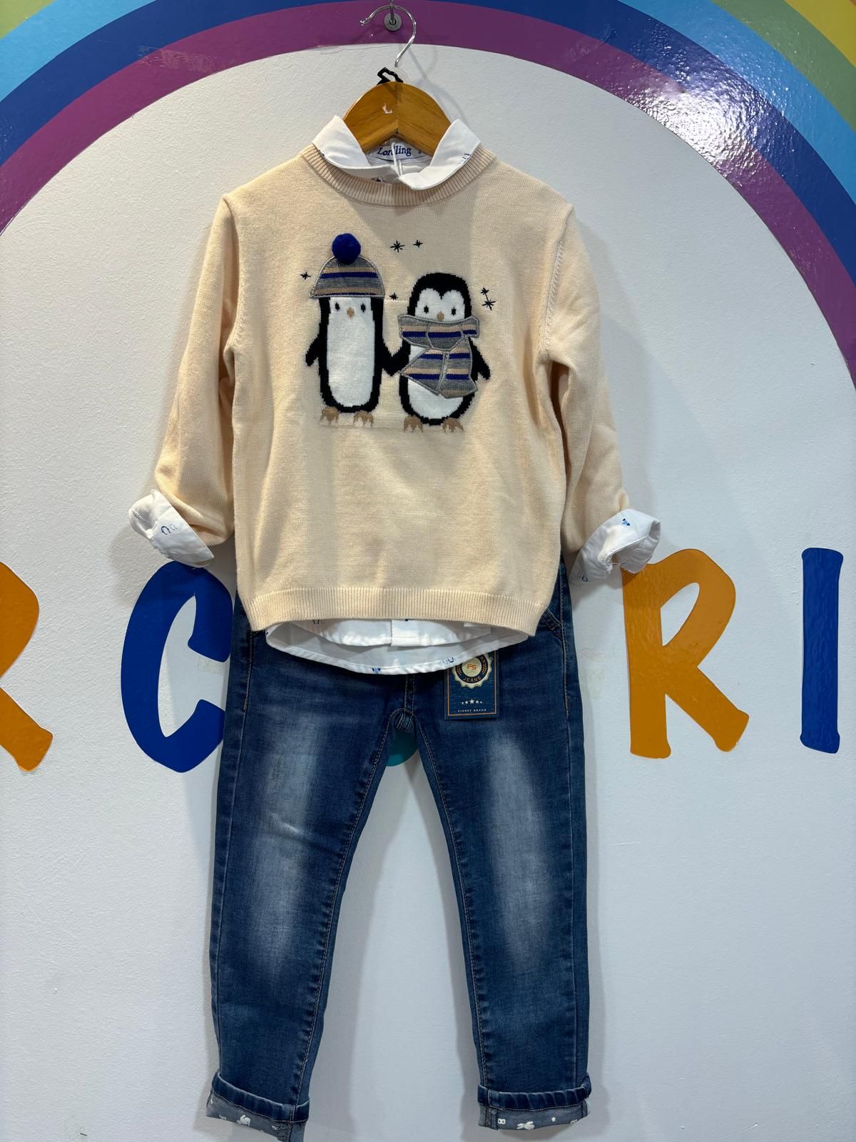 Un suéter con pingüinos está colgado en una percha.