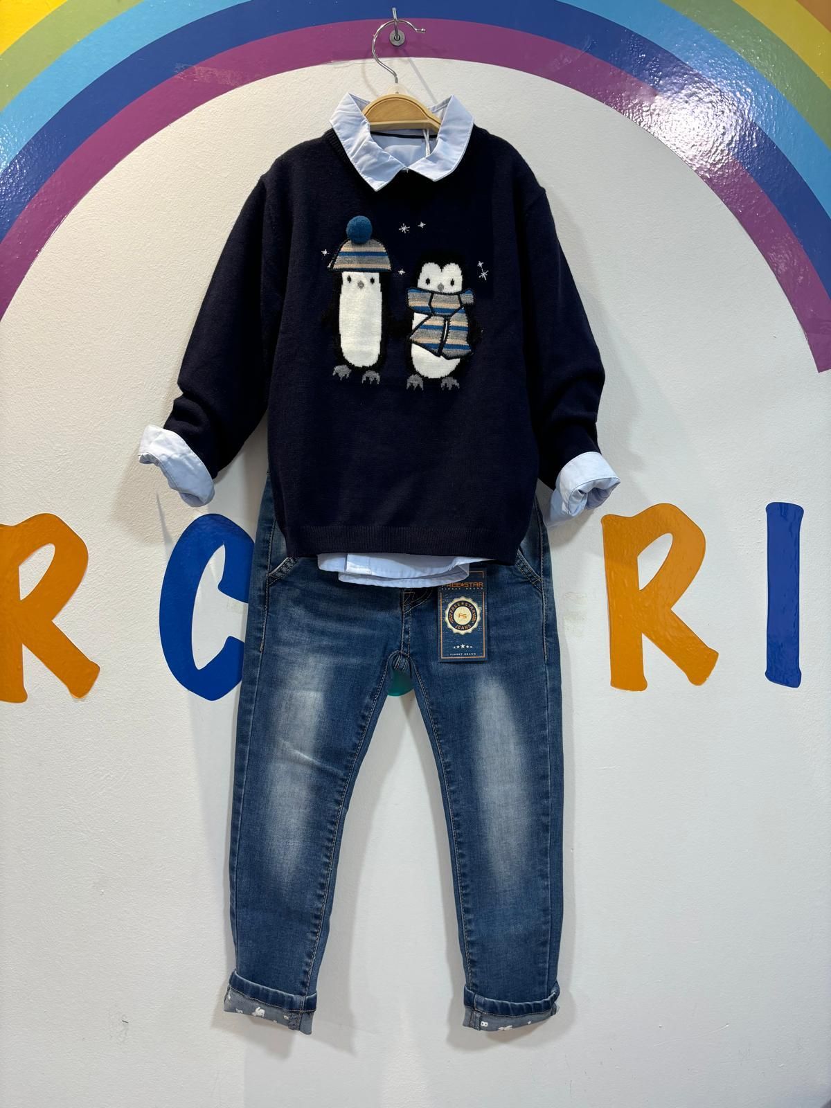 Un suéter con pingüinos está colgado en una percha.