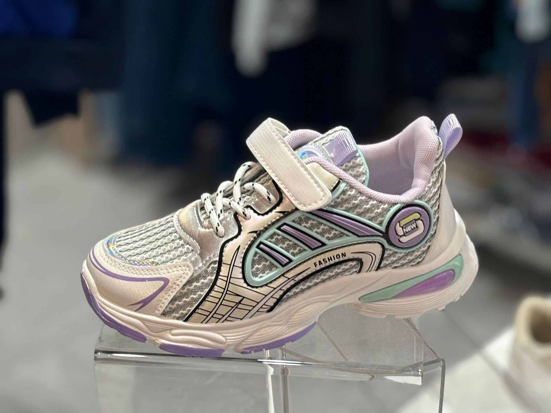 Un par de zapatillas blancas y moradas se encuentran encima de una vitrina transparente.