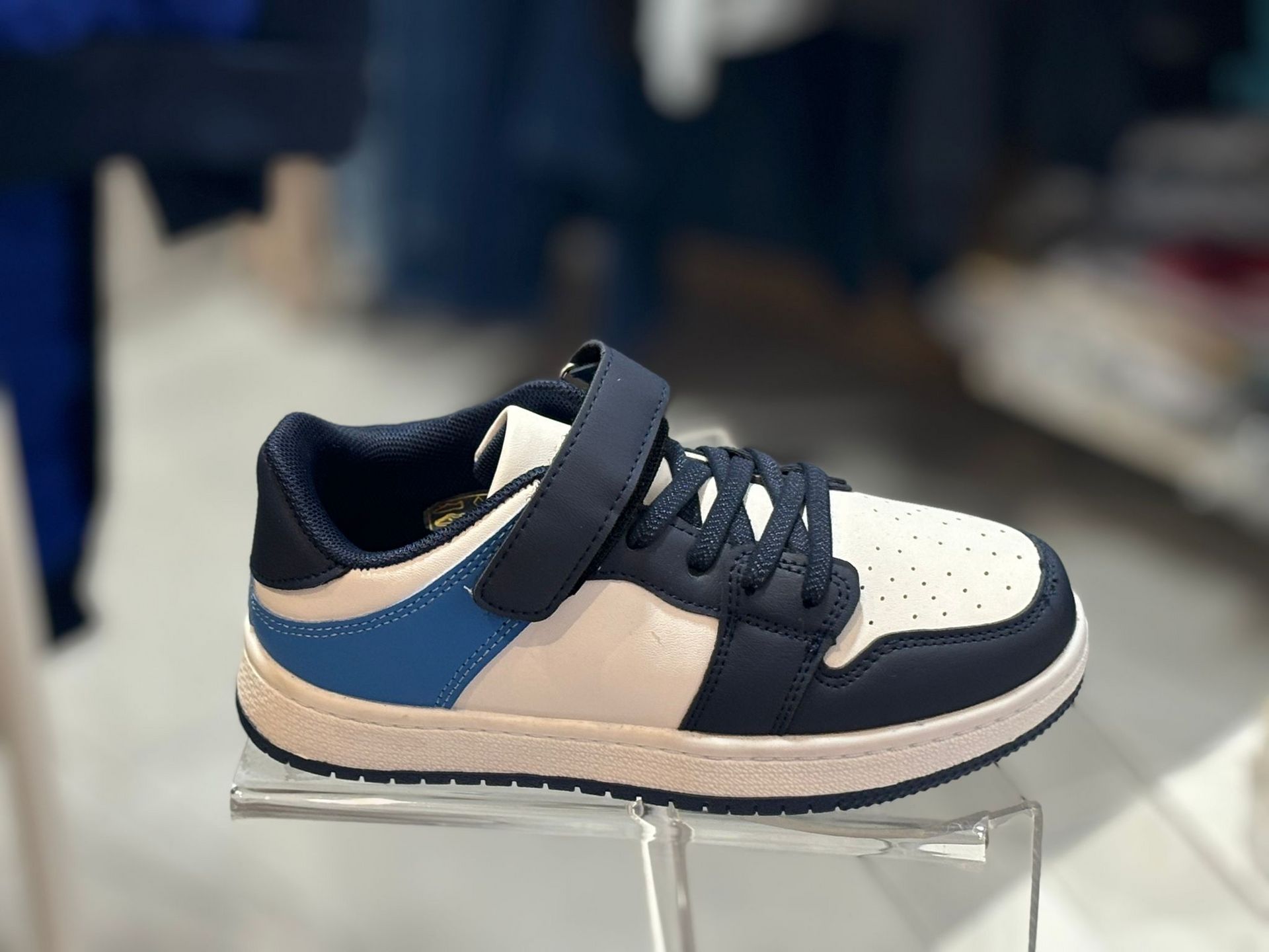 Un par de zapatillas azules y blancas en exhibición en una tienda.