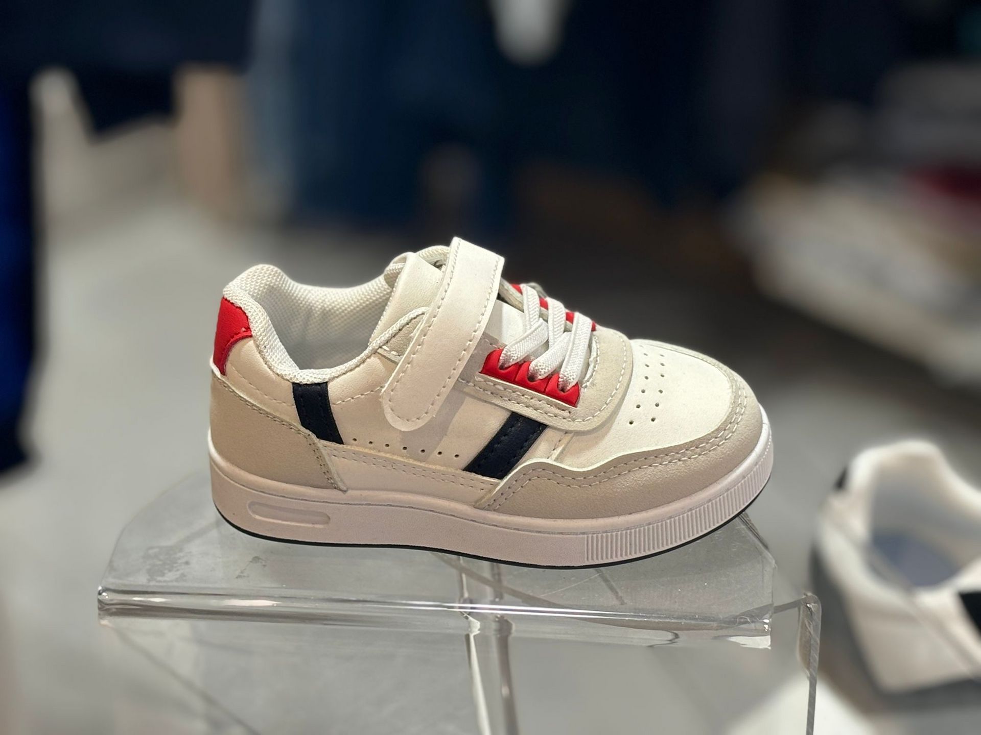 Un par de zapatillas blancas y rojas se encuentran en una exhibición transparente.