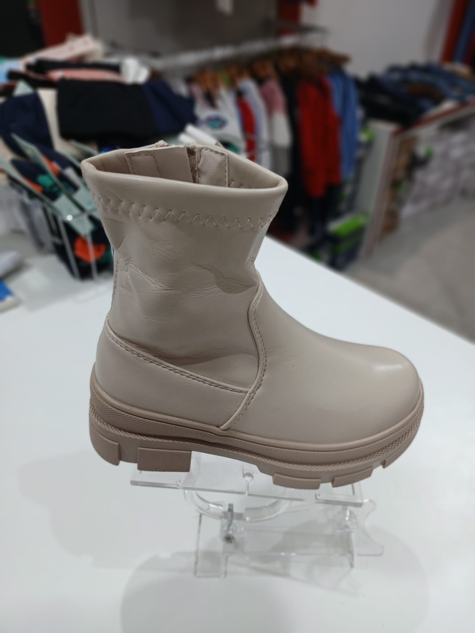 Un par de botas de color beige se encuentran sobre una mesa blanca.