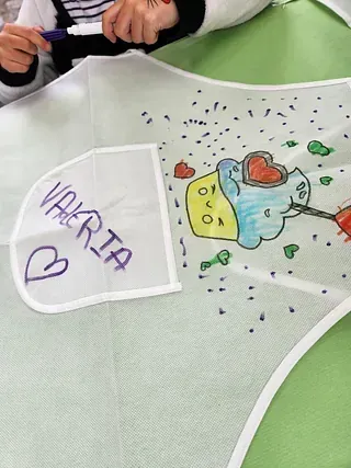 Un niño está cortando un trozo de papel con el nombre Valeria escrito en él.