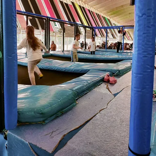 Un grupo de niños está jugando en un parque de trampolines.