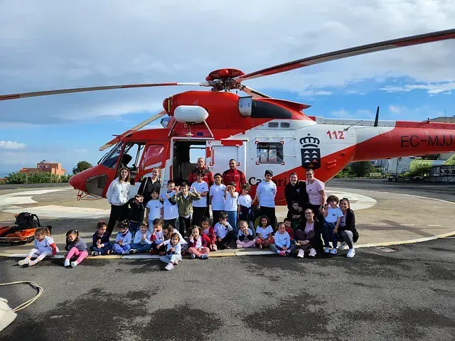 Un grupo de niños posa para una fotografía frente a un helicóptero.