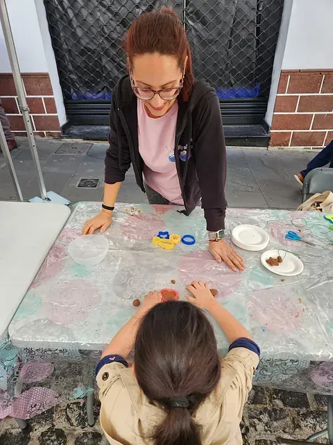 Una mujer está de pie junto a una niña sentada en una mesa.