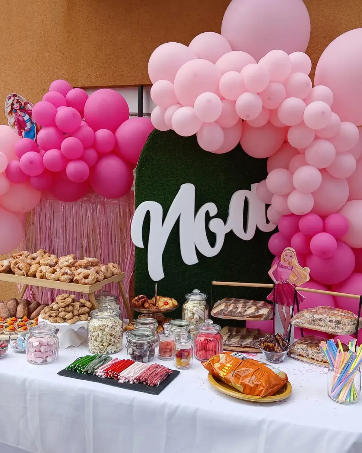 Una mesa con globos rosas y un cartel que dice noa