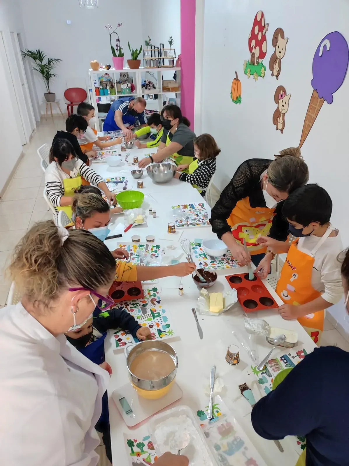 Un grupo de personas está sentado alrededor de una mesa en una habitación con conos de helado en la pared.