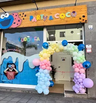 Un escaparate con globos y un cartel que dice fiesta y coco