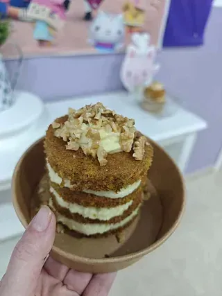 Una persona sostiene un pastel pequeño en un plato.