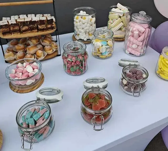 Una mesa llena de frascos llenos de diferentes tipos de dulces.