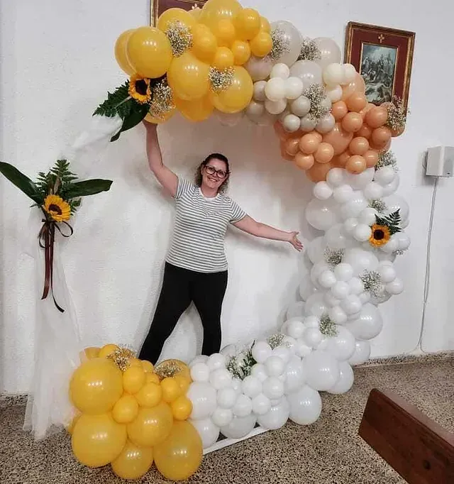 Una mujer está parada frente a un arco de globos.
