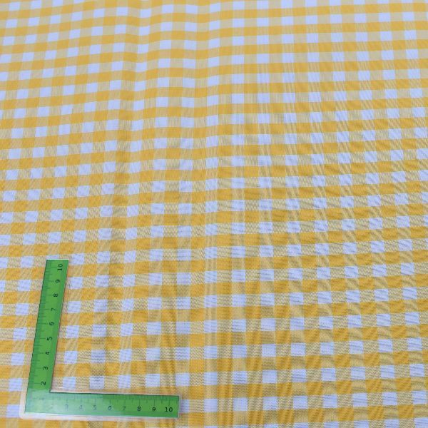 Una regla verde está colocada encima de un mantel a cuadros amarillo y blanco.