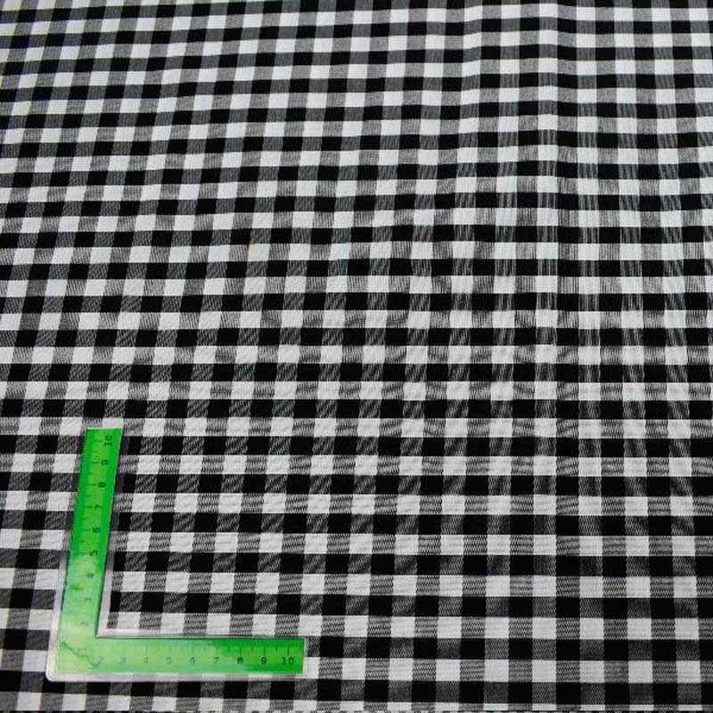 Una regla verde está colocada encima de una tela a cuadros blanca y negra.