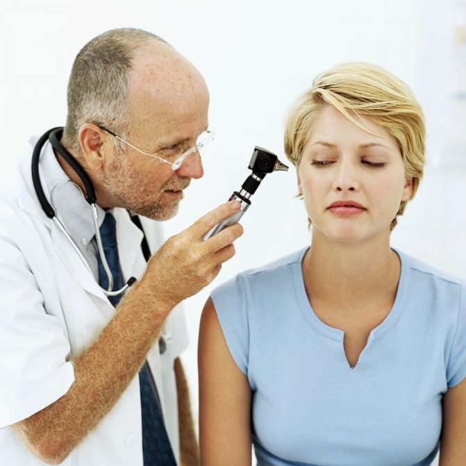 Médico examinando o ouvido de um paciente com um otoscópio. O paciente fecha os olhos.