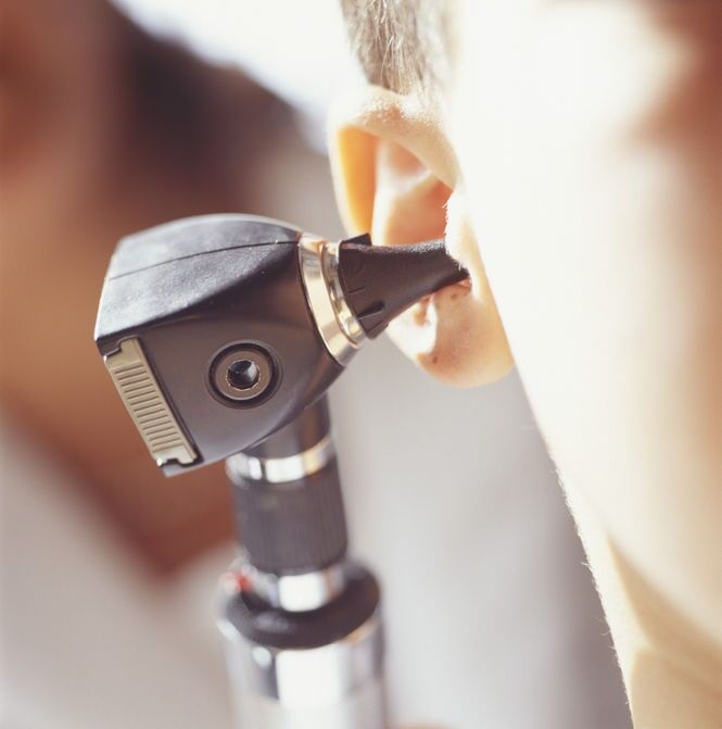 Um otoscópio examina o ouvido do paciente.